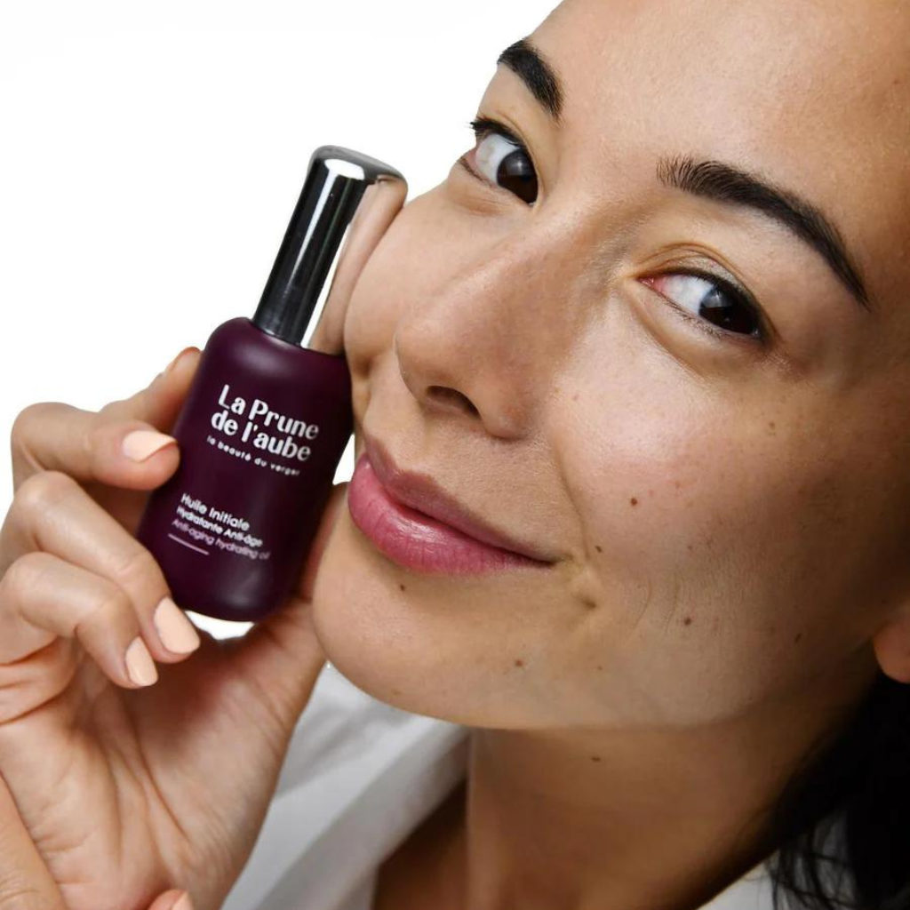 femme brune tenant proche de son visage un flacon de l&