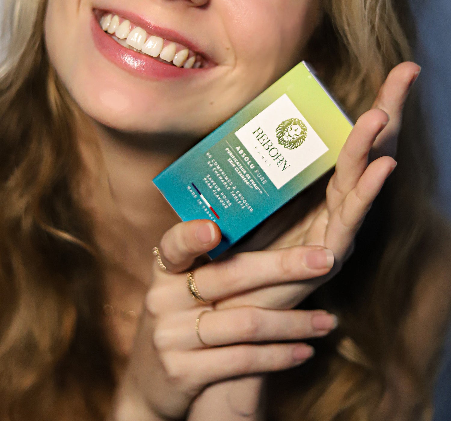 femme tenant une boîte verte de compléments alimentaires Absolu Pure pour lutter contre ses boutons