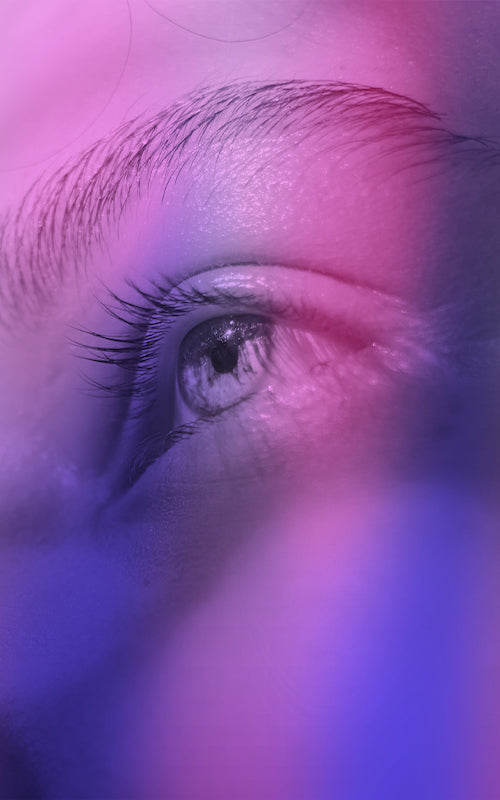 zoom sur un oeil bleu avec joli regard surmonté d'un sourcil sous des teintes violet/rose