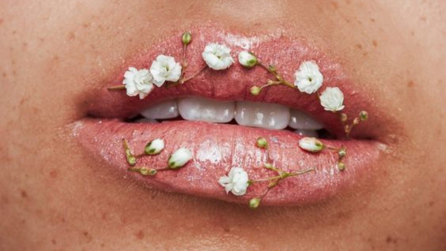 lèvre sur lequelles sont déposées artistiquement de petites fleurs blanches, évoquant la naturalité d'un soin, aussi bien intérieur qu'extérieur